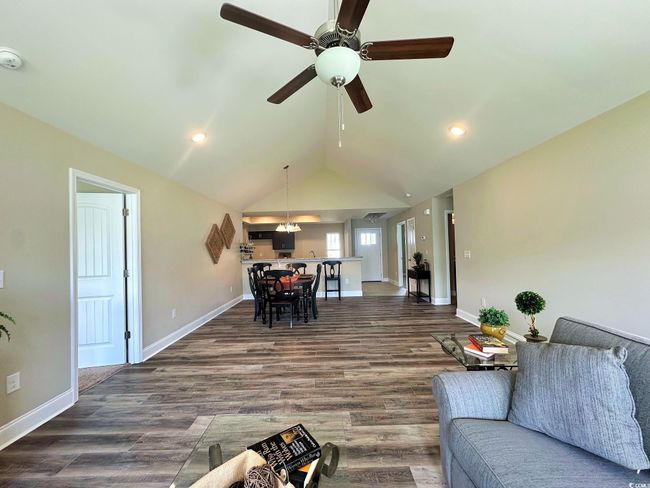 Living room featuring dark wood-style flooring, baseboards, vaulted ceiling, recessed lighting, and a ceiling fan | Image 6
