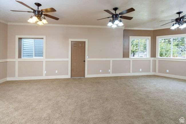 Carpeted family room with a textured ceiling, crown molding, and ceiling fan | Image 32