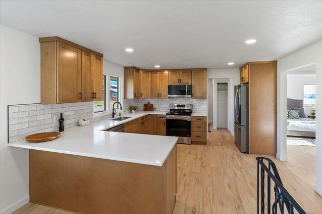 Kitchen with appliances with stainless steel finishes, kitchen peninsula, sink, and light hardwood / wood-style flooring | Image 16