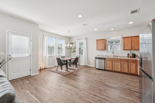 Kitchen featuring stainless steel appliances, a chandelier, brown cabinetry, light countertops, and light wood-style floors | Image 9