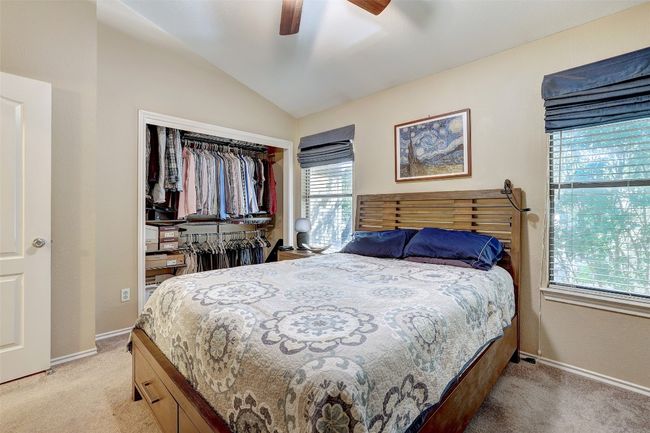 Bedroom with light colored carpet, vaulted ceiling, a closet, baseboards, and ceiling fan | Image 20