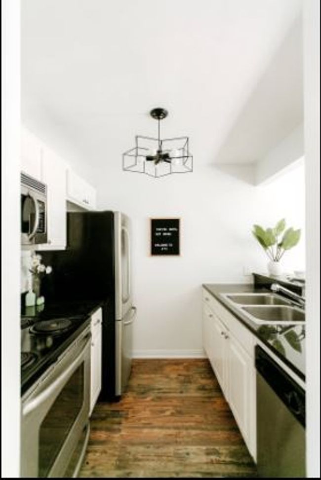 Kitchen featuring stainless steel appliances, a chandelier, white cabinets, and brick flooring | Image 8
