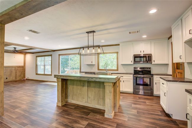 Kitchen featuring appliances with stainless steel finishes, dark wood-style flooring, white cabinetry, ceiling fan, and recessed lighting | Image 6