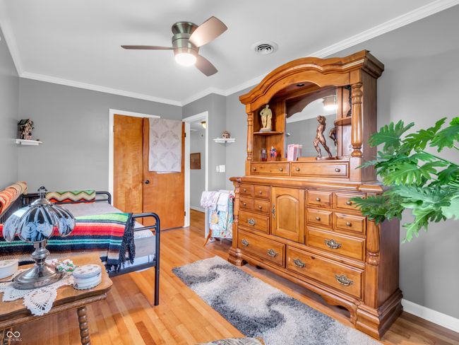 bedroom featuring ceiling fan, light wood-type flooring, visible vents, baseboards, and ornamental molding | Image 26