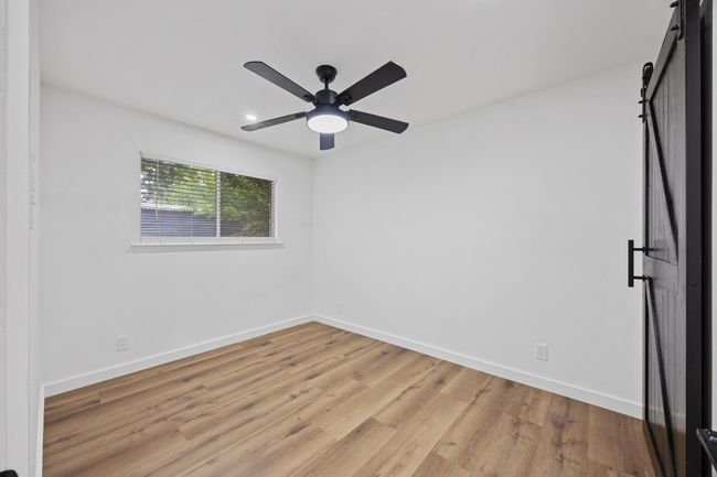 Unfurnished room featuring a barn door, light wood-style flooring, and a ceiling fan | Image 26