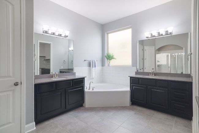 Full bathroom featuring a stall shower, two vanities, tile patterned flooring, and a garden tub | Image 18