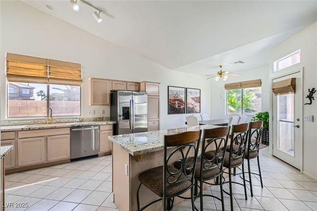 Kitchen featuring stainless steel appliances, a sink, light tile patterned floors, a kitchen bar, and a center island | Image 9