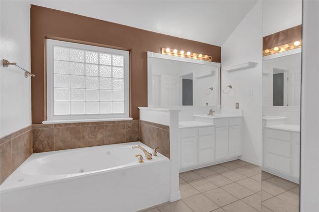Full bath featuring vanity, tile patterned floors, a garden tub, and vaulted ceiling | Image 24