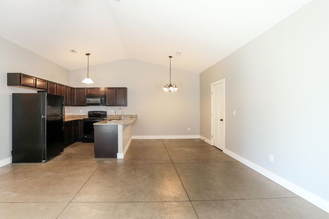 Kitchen with dark brown cabinetry, sink, hanging light fixtures, and black appliances | Image 9