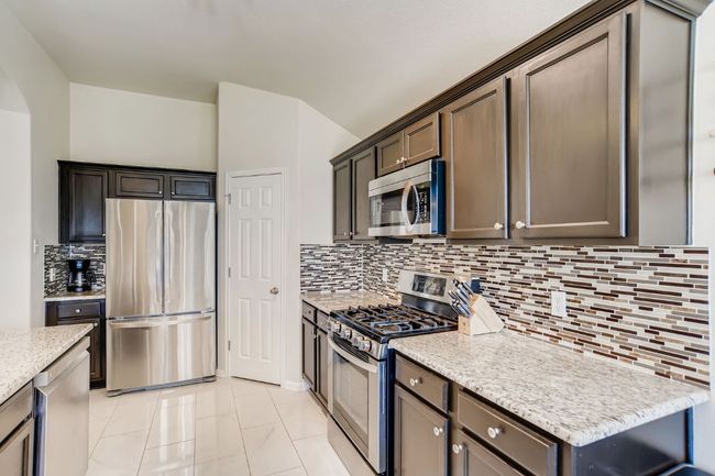 Kitchen with stainless steel appliances, decorative backsplash, light stone countertops, arched walkways, and light marble finish floors | Image 8
