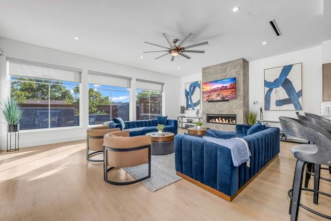 Living room featuring a tiled fireplace, ceiling fan, plenty of natural light, and light wood-type flooring | Image 9