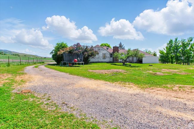 View of front facade featuring a trampoline, gravel driveway, a chimney, and a view of countryside | Image 21