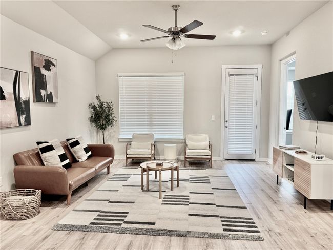 Living room with wood finished floors, baseboards, ceiling fan, and lofted ceiling | Image 13