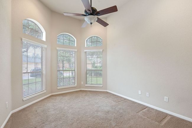 Carpeted spare room with a ceiling fan, baseboards, and a towering ceiling | Image 10
