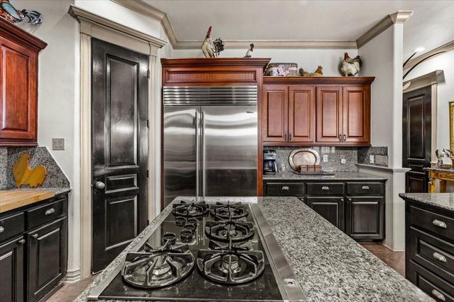 Rosewood cabinets, and heavy pewter cabinet cup pulls add an extra touch of style to English manor look of this home. | Image 16