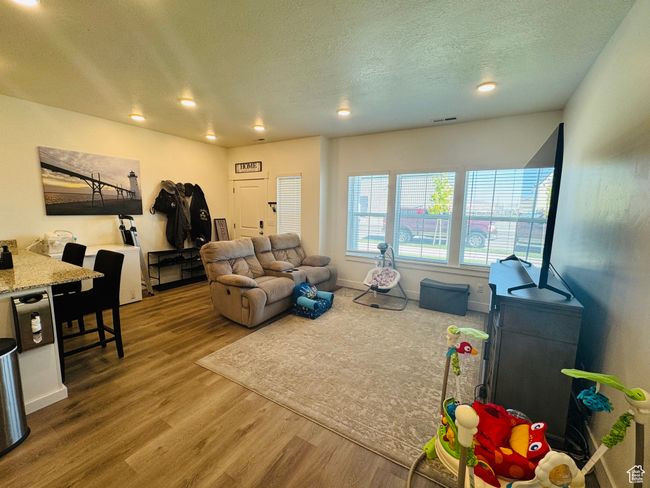 Living room with wood finished floors, a textured ceiling, and recessed lighting | Image 7