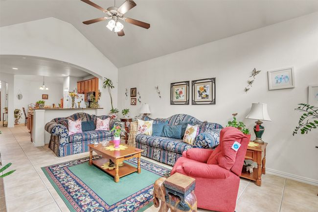 Living room with light tile patterned flooring, a ceiling fan, high vaulted ceiling, and arched walkways | Image 7