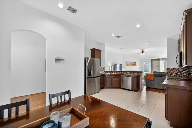 Kitchen with stainless steel appliances, decorative backsplash, ceiling fan, a peninsula, and dark countertops | Image 11