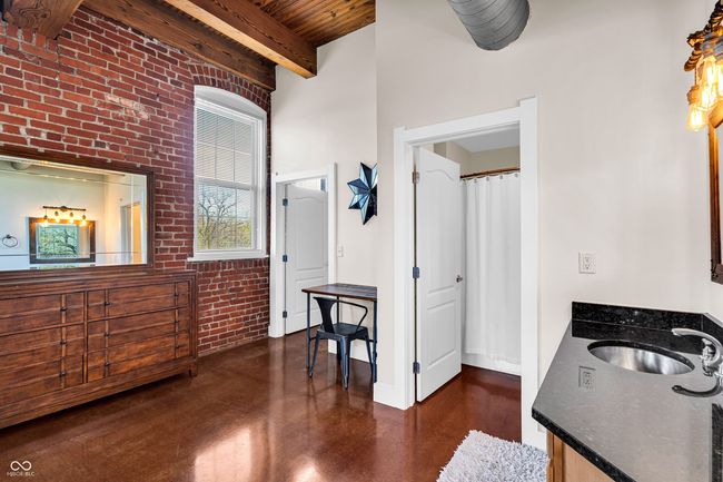 bathroom featuring beam ceiling, vanity, wood ceiling, and brick wall | Image 13