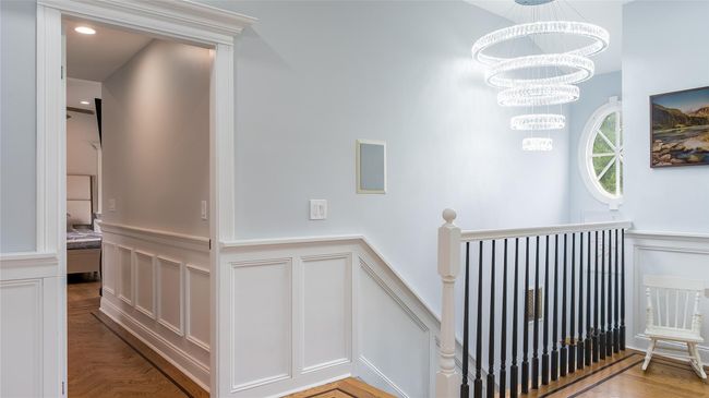 Stairs featuring a decorative wall, a wainscoted wall, and a chandelier | Image 18