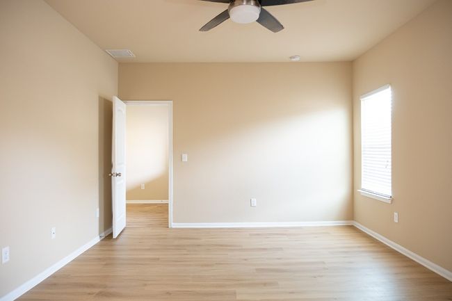 Empty room with ceiling fan, light wood finished floors, and baseboards | Image 13