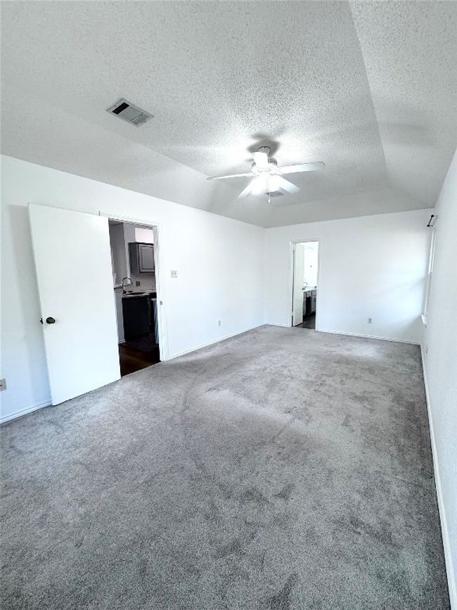 Unfurnished bedroom with carpet floors, a textured ceiling, ensuite bath, and ceiling fan | Image 14