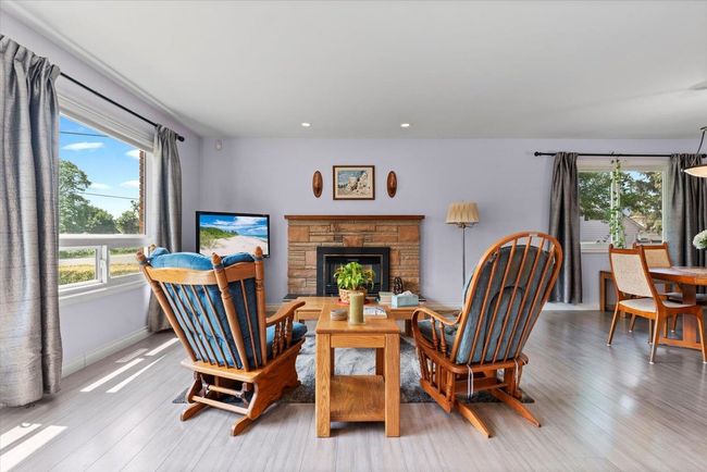 Living area with plenty of natural light, light wood-style floors, recessed lighting, and a fireplace | Image 11