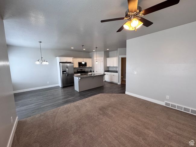Kitchen featuring a kitchen island with sink, appliances with stainless steel finishes, a sink, dark carpet, and open floor plan | Image 10