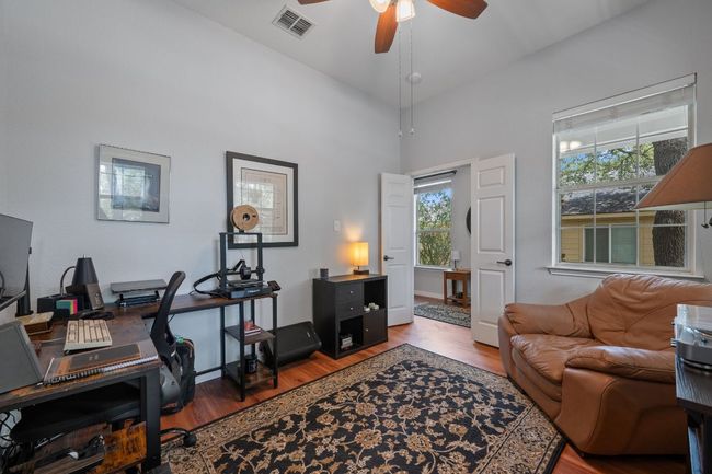 Home office with wood finished floors, a ceiling fan, and a high ceiling | Image 25