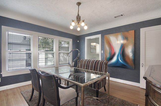 Dining area with a textured ceiling, visible vents, baseboards, wood finished floors, and an inviting chandelier | Image 16