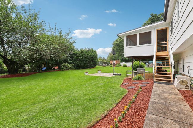 Rear view of property with a sunroom, stairs, a patio area, and view of scattered trees | Image 28