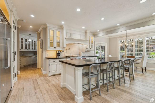 Kitchen with dark countertops, light wood finished floors, ornamental molding, tasteful backsplash, and recessed lighting | Image 14