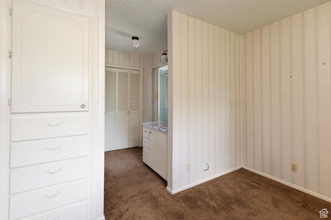 Unfurnished bedroom with dark carpet, a textured ceiling, and wallpapered walls | Image 12