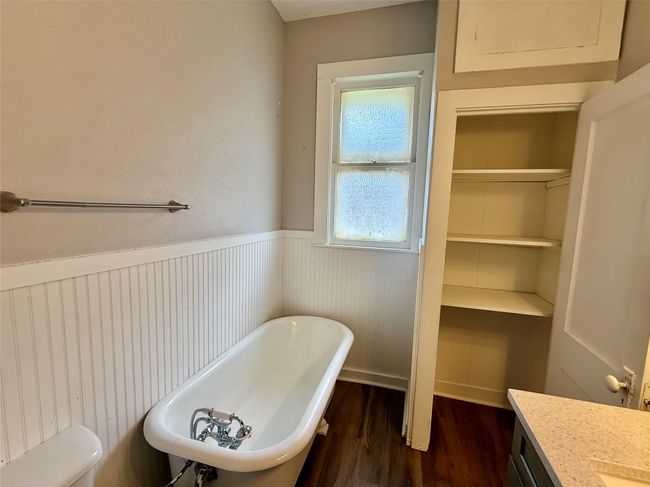 Full bathroom featuring a soaking tub, wood finished floors, wainscoting, and vanity | Image 9