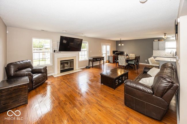 living area featuring a tile fireplace, hardwood / wood-style floors, baseboards, and a notable chandelier | Image 4