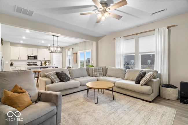 living area with light wood-style floors, a ceiling fan, recessed lighting, and a chandelier | Image 10