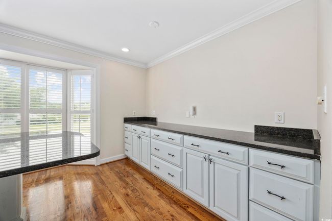 Kitchen with crown molding, wood finished floors, white cabinetry, baseboards, and dark stone countertops | Image 20