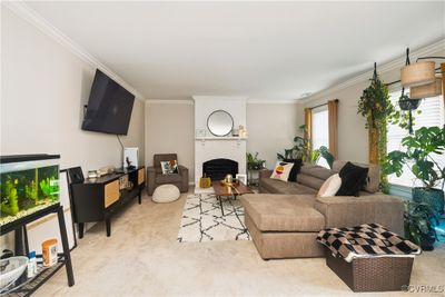 Living room with ornamental molding, a brick fireplace, and light colored carpet | Image 2