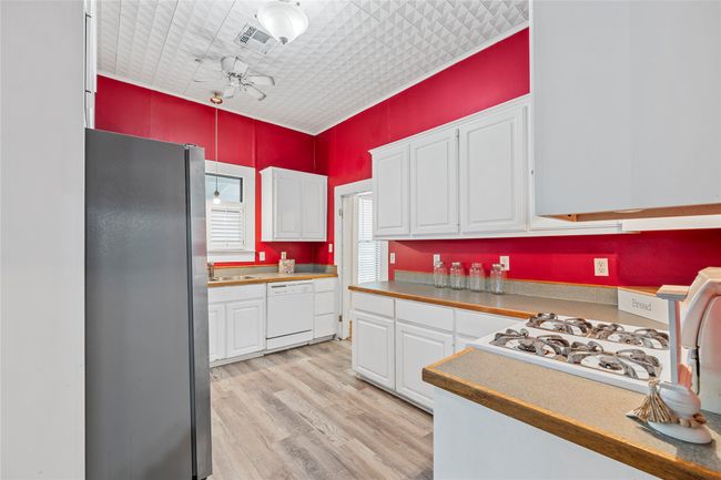 Kitchen featuring freestanding refrigerator, white dishwasher, white cabinets, light wood-type flooring, and ceiling fan | Image 17