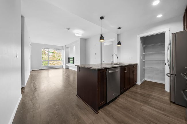 Kitchen with stainless steel appliances, a sink, open floor plan, dark wood finished floors, and baseboards | Image 19