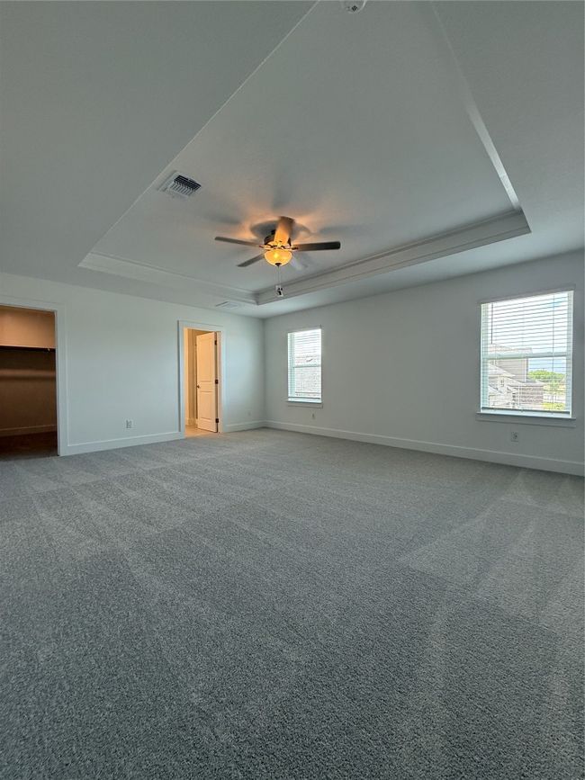Empty room with a tray ceiling, baseboards, carpet flooring, and a ceiling fan | Image 23