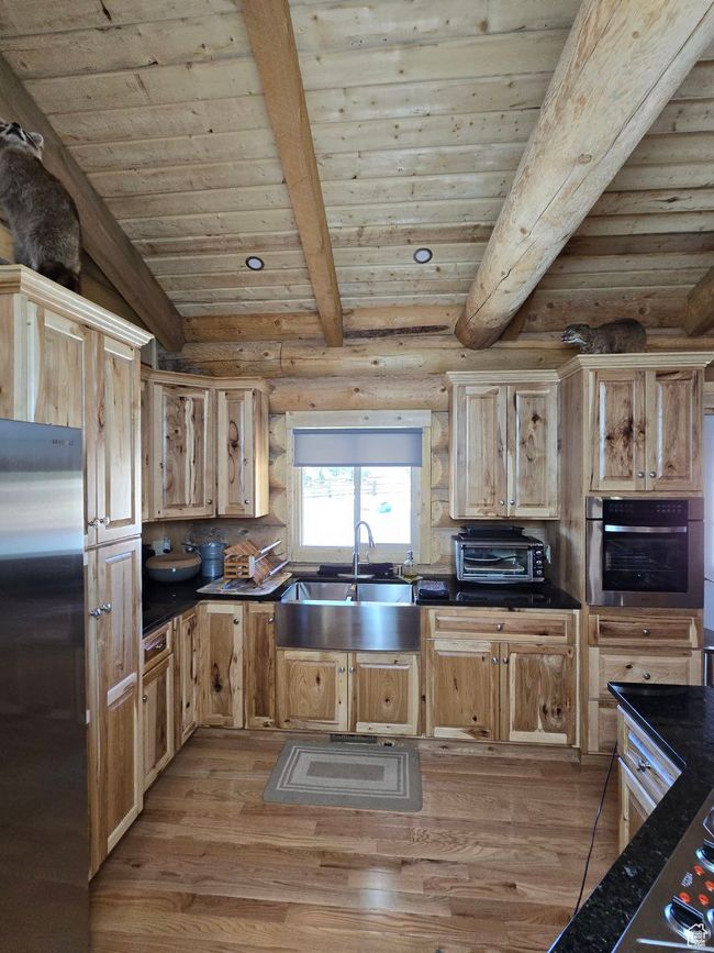 Kitchen with a sink, log walls, dark countertops, and appliances with stainless steel finishes | Image 59