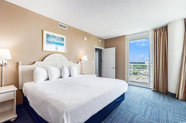 Bedroom featuring access to exterior, dark colored carpet, and a textured ceiling | Image 15