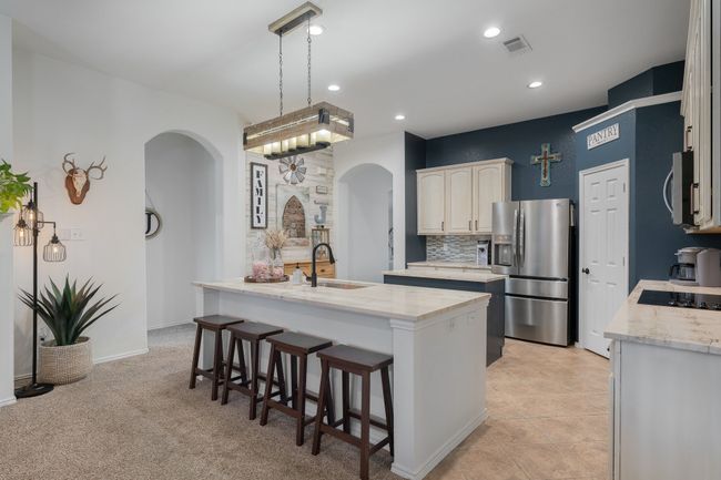 Kitchen with arched walkways, a sink, stainless steel appliances, a center island with sink, and a kitchen breakfast bar | Image 14