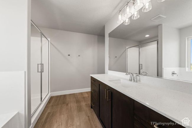 Bathroom with vanity, a shower stall, wood finished floors, a garden tub, and baseboards | Image 16