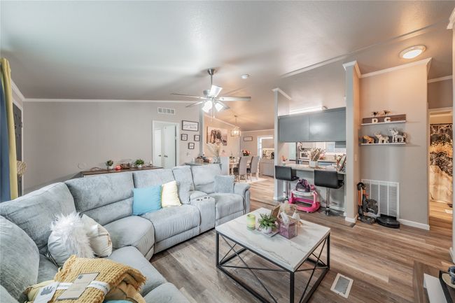 Living area featuring light wood-style flooring, ceiling fan, crown molding, and vaulted ceiling | Image 6