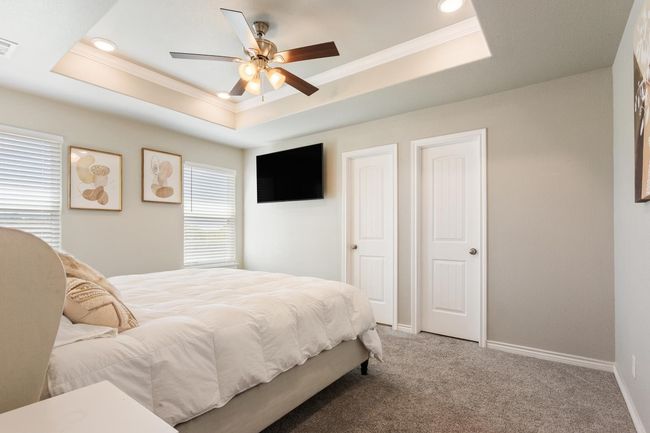 Bedroom featuring a raised ceiling, crown molding, light colored carpet, a ceiling fan, and recessed lighting | Image 18