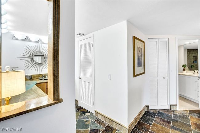 Hallway featuring stone tile floors, baseboards, a sink, and visible vents | Image 11