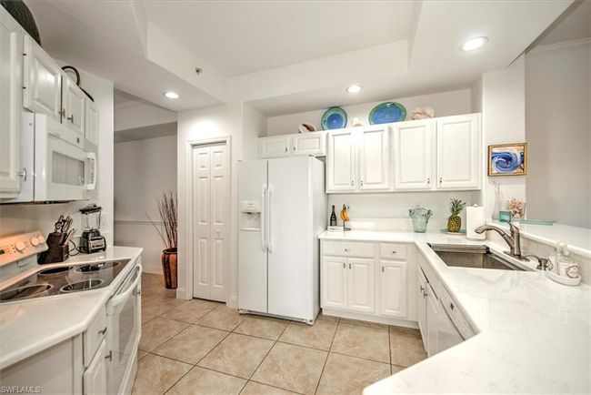 Kitchen with a sink, white cabinetry, light tile patterned floors, white appliances, and recessed lighting | Image 9