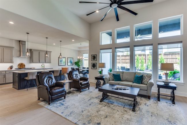 Living area with light wood finished floors, recessed lighting, a high ceiling, and a chandelier | Image 12